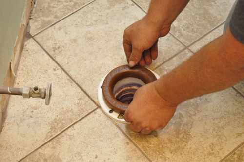 Man installing a new toilet placing wax ring. 