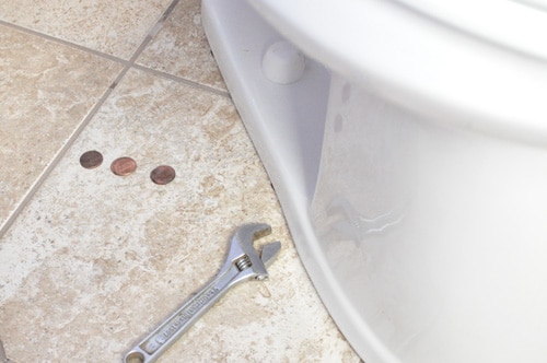 Toilet seat leveling using pennies and crescent wrench.