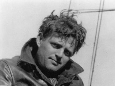 A man in a leather jacket, engrossed in reading a book by Jack London.