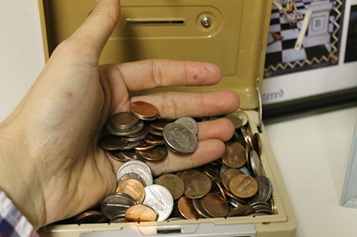 Man hand sorting through coin bank. 