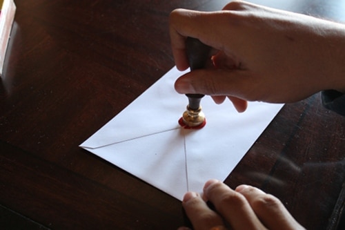 Pressing stamp into melted wax. 