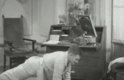 An old black and white photo of a man starting his day with push ups.