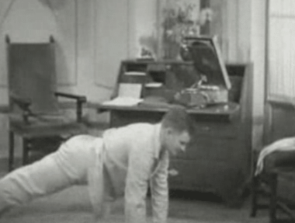 An old black and white photo of a man starting his day with push ups.