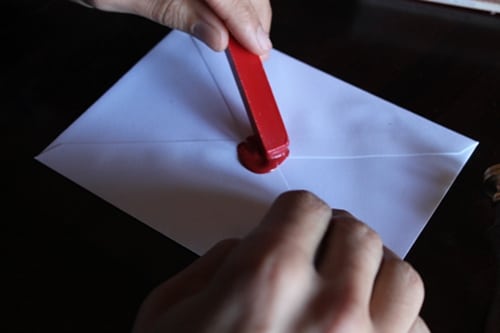 Pasting melted wax on envelope to seal.