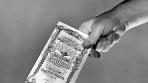 A hand holding a stock market primer.