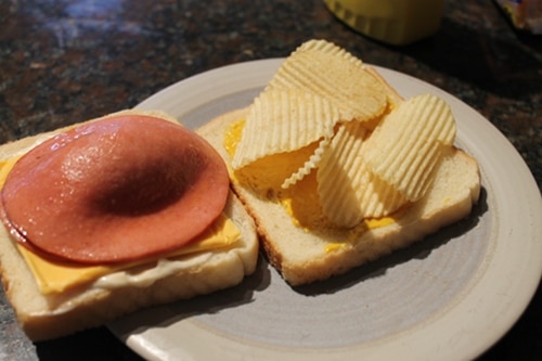 Fried bologna sandwich with cheese and potato chips. 