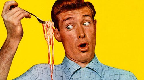 A man is enjoying a bowl of spaghetti while dealing with common clothing stains.