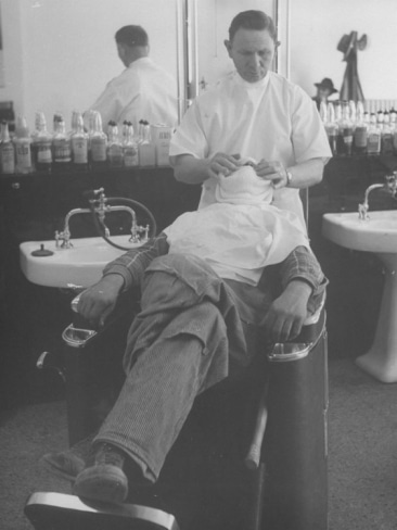 Create a Barbershop experience with a man getting a haircut and enjoying the soothing sensation of a hot towel.