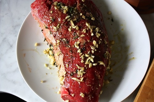 Coat meat with a few tablespoons of olive oil. Next, add minced garlic and thyme, followed by a liberal sprinkling of kosher salt and fresh cracked pepper. Keep the meat out of the fridge! You want it to be at room temperature to create a nice sear and so it will cook evenly.