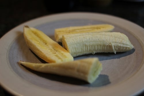 Vintage cutting banana in half lengthwise.
