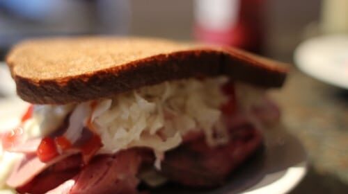 A sandwich with meat and coleslaw, part of the AoM Month of Sandwiches event, served on a plate.
