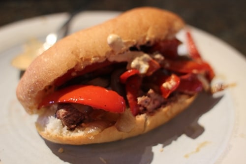 A Drunken Steak Sandwich with peppers and cheese on a plate.