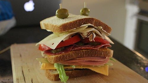 An All-American Dagwood sandwich is sitting on top of a cutting board.