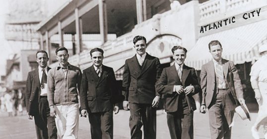 A group of men walking on a boardwalk in a new city.