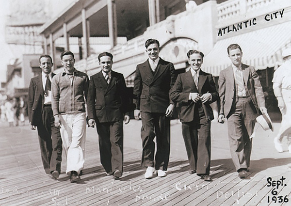 A group of men walking on a boardwalk in a new city.
