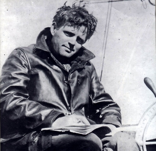 Jack London sitting writing in notebook on yacht.