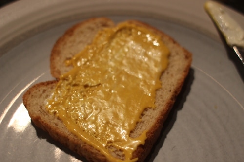 Vintage spread mustard on second slice of bread.