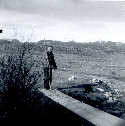 lderly old man walking with stick across wooden bridge in mountains.