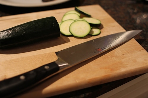 Vintage thinly slice zucchini and knife placed at cutting board.