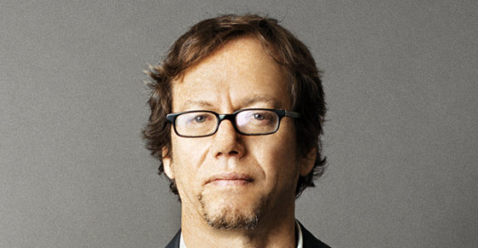 A man in glasses poses for a photo, embodying the Art of Manliness.