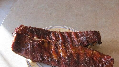 Smoked ribs sitting on a plate on a table.