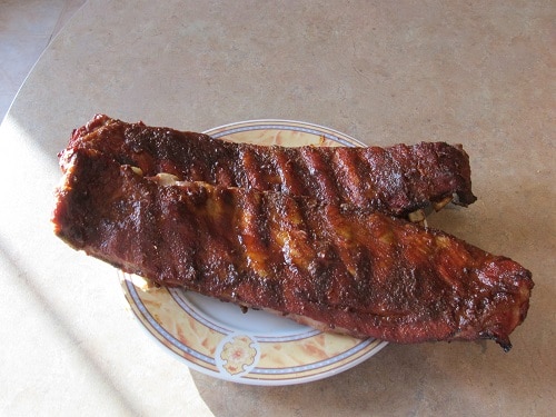 Smoked ribs sitting on a plate on a table.