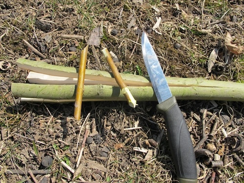 Vintage knife and small sticks placed on earth.