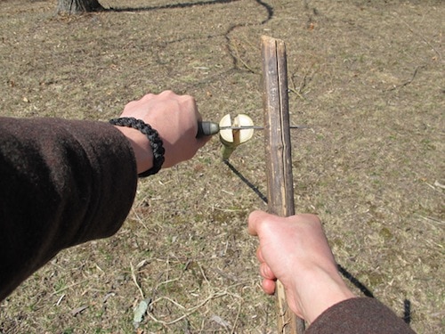 Vintage man holding knife and cutting sapling into four pieces.