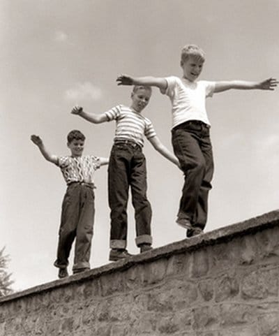 Vintage boys kids walking balancing along brick ball.