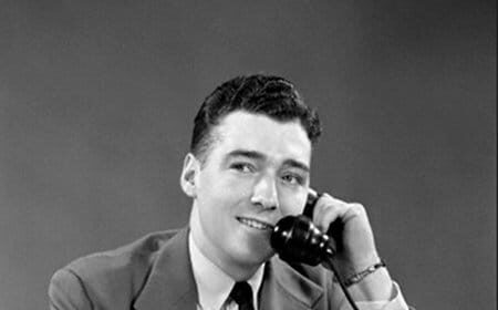 A man in a suit and tie on his first day at a new job, talking on the phone.