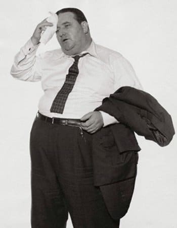 Vintage overweight man wiping brow with handkerchief.