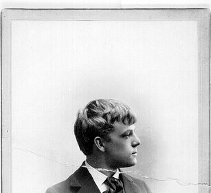 An old photograph capturing a young man in a suit, exuding an aura of Manvotional – embodying the spirit and potential of the Coming Man of the World.