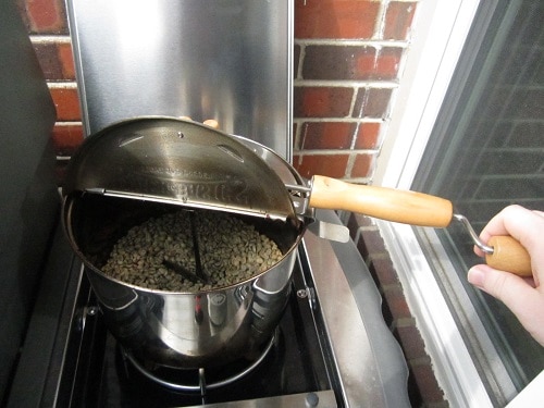 Roasting green coffee beans in popcorn popper on grill. 