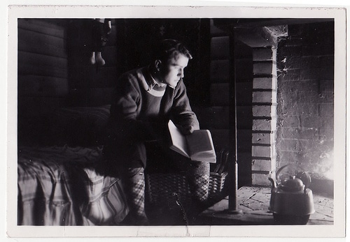 Vintage man reading book by a fireplace contemplating.
