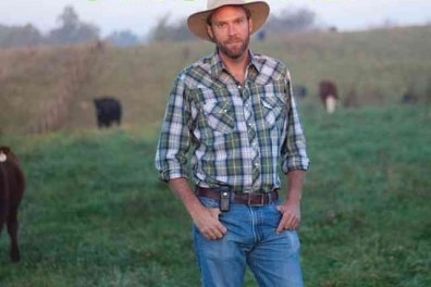 A man in a cowboy hat standing in a field with cows on a Family Farm.
