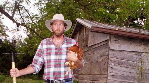 A man in a cowboy hat standing in front of a chicken coop, starting his own farm by following the rules.