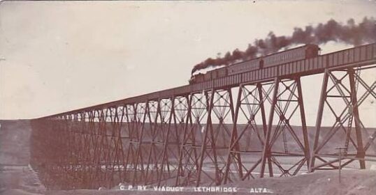 An old photo capturing the art of a train traveling over a bridge.