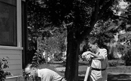 Two men using a reel mower to sharpen and mow the lawn.
