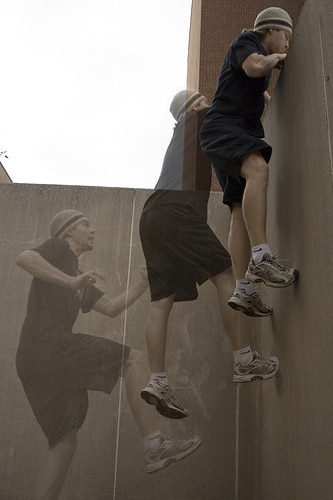 A young boy climbing over a wall.