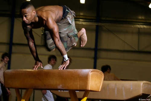 Afrikaans-Amerikaanse zwarte man springt over pommel horse parkour.