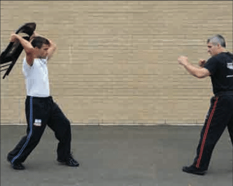 Two men practicing Krav Maga technique in front of a brick wall.
