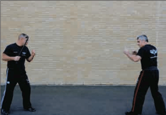 Two men practicing Krav Maga in front of a brick wall, showcasing their Strike Defense technique.