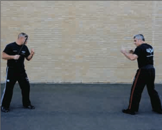 Two men practicing Krav Maga in front of a brick wall, showcasing their Strike Defense technique.
