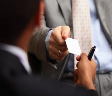 man handing business card to another person close up 