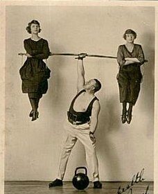 An old photo of a man and two women participating in balanced strength training with a kettlebell exercise.