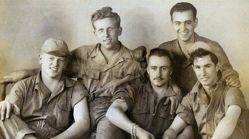 A group of men, friends in military uniforms, posing for a photo.