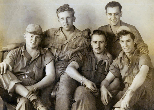 A group of men, friends in military uniforms, posing for a photo.