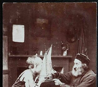 A timeless photo capturing the nostalgic bond between a man and a boy as they joyfully play with a sailboat.