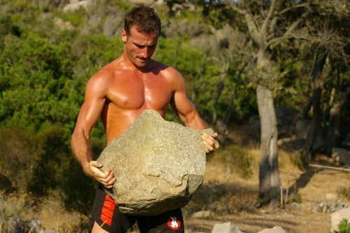 Man carrying large stone working out.