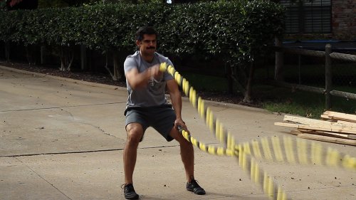 Vintage men alternate moving his arms up and down as fast rope for exercise.